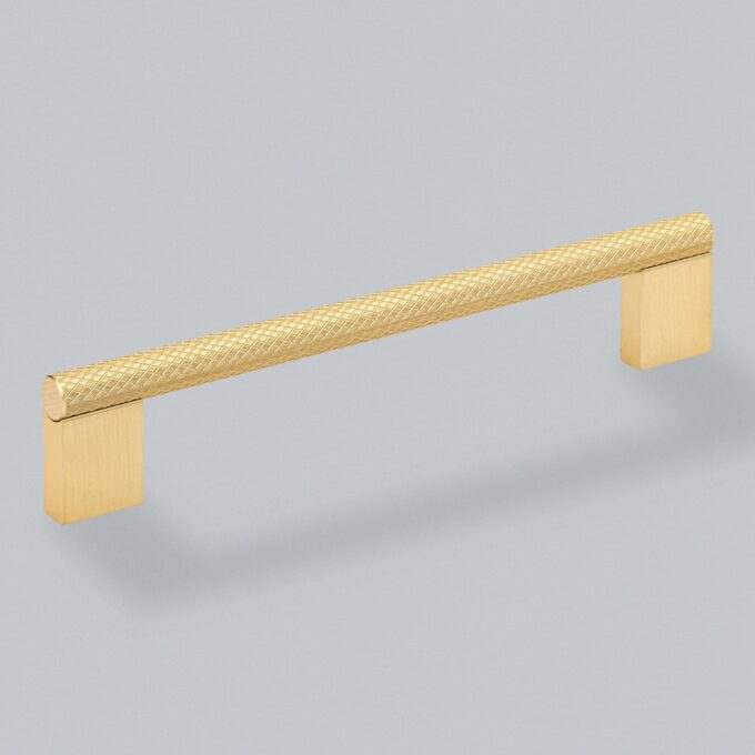 Textured gold cabinet handle on a grey background.