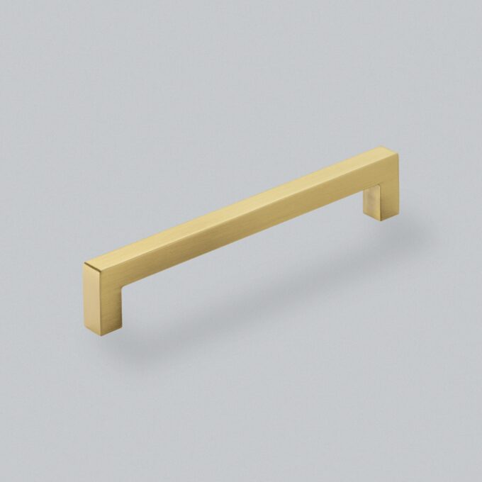 Brushed gold cabinet handle on grey background.