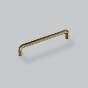 Antique brass cabinet handle on grey background.