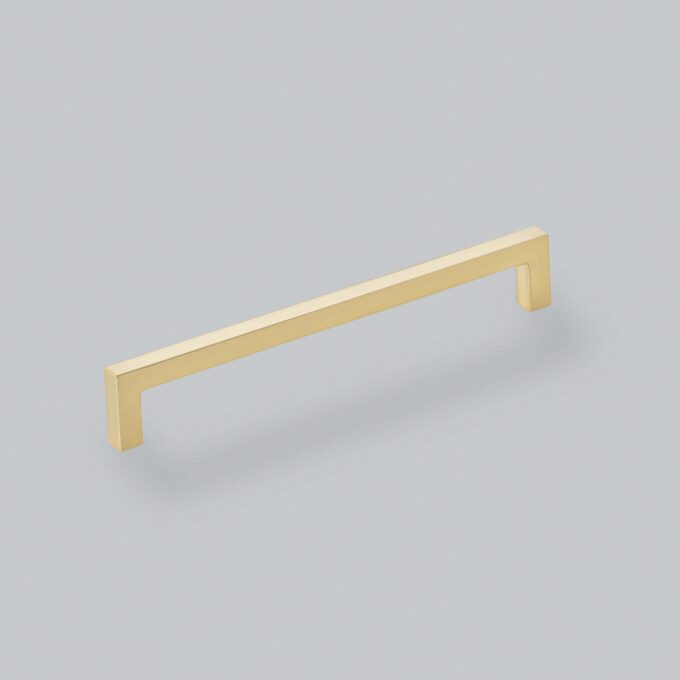 Gold cabinet handle on grey background.