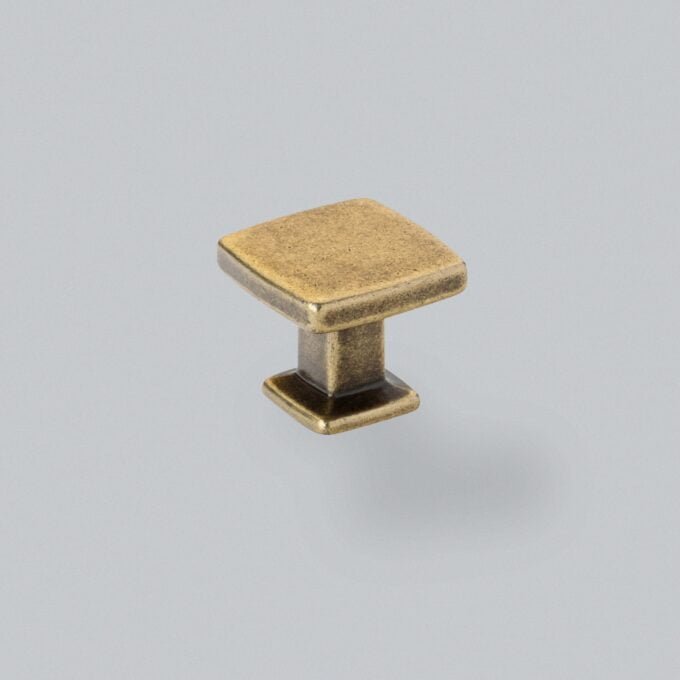 Antique brass drawer knob on grey background.