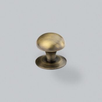 Antique brass cabinet knob on grey background.