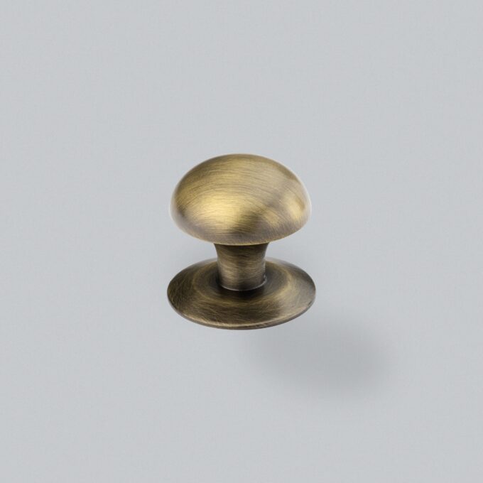 Antique brass cabinet knob on grey background.