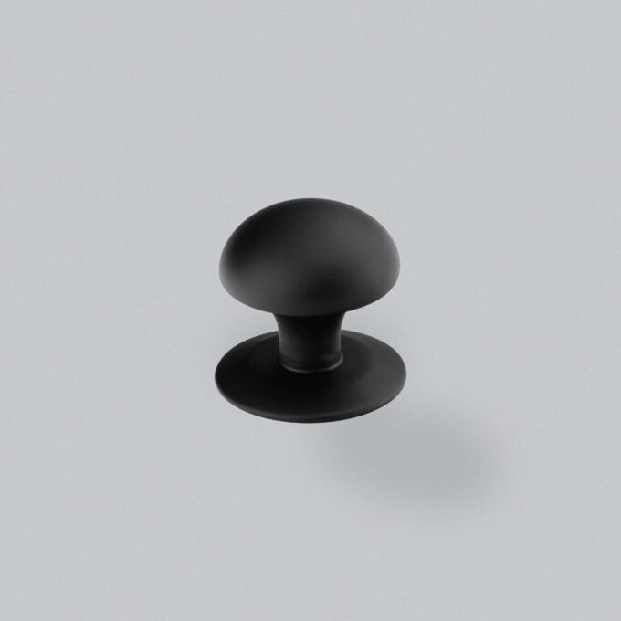 Black round cabinet knob on grey background.