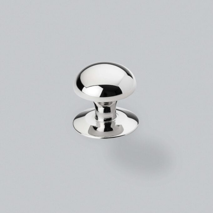 Polished chrome cabinet knob on grey background.