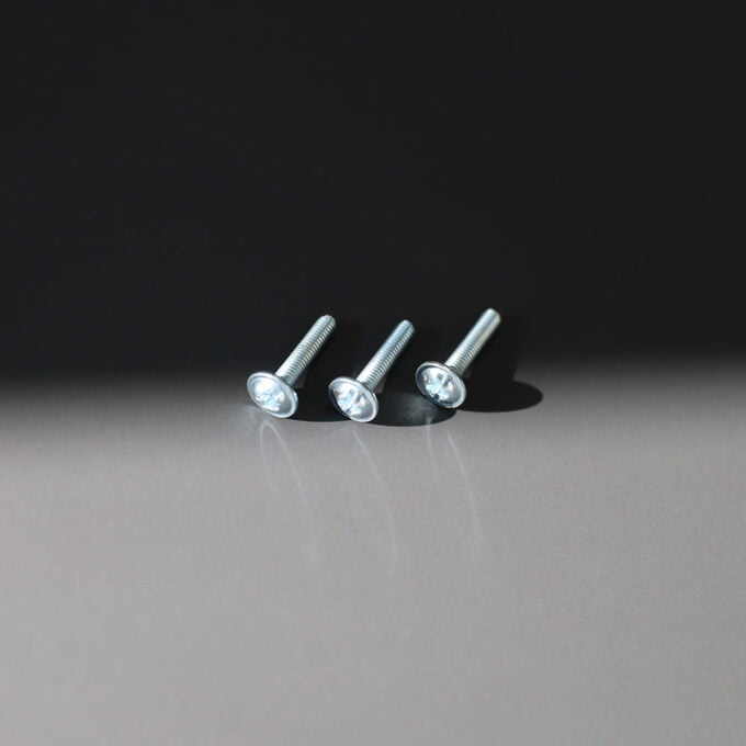 Three silver screws on grey surface.