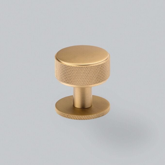 Textured gold cabinet knob on grey background.