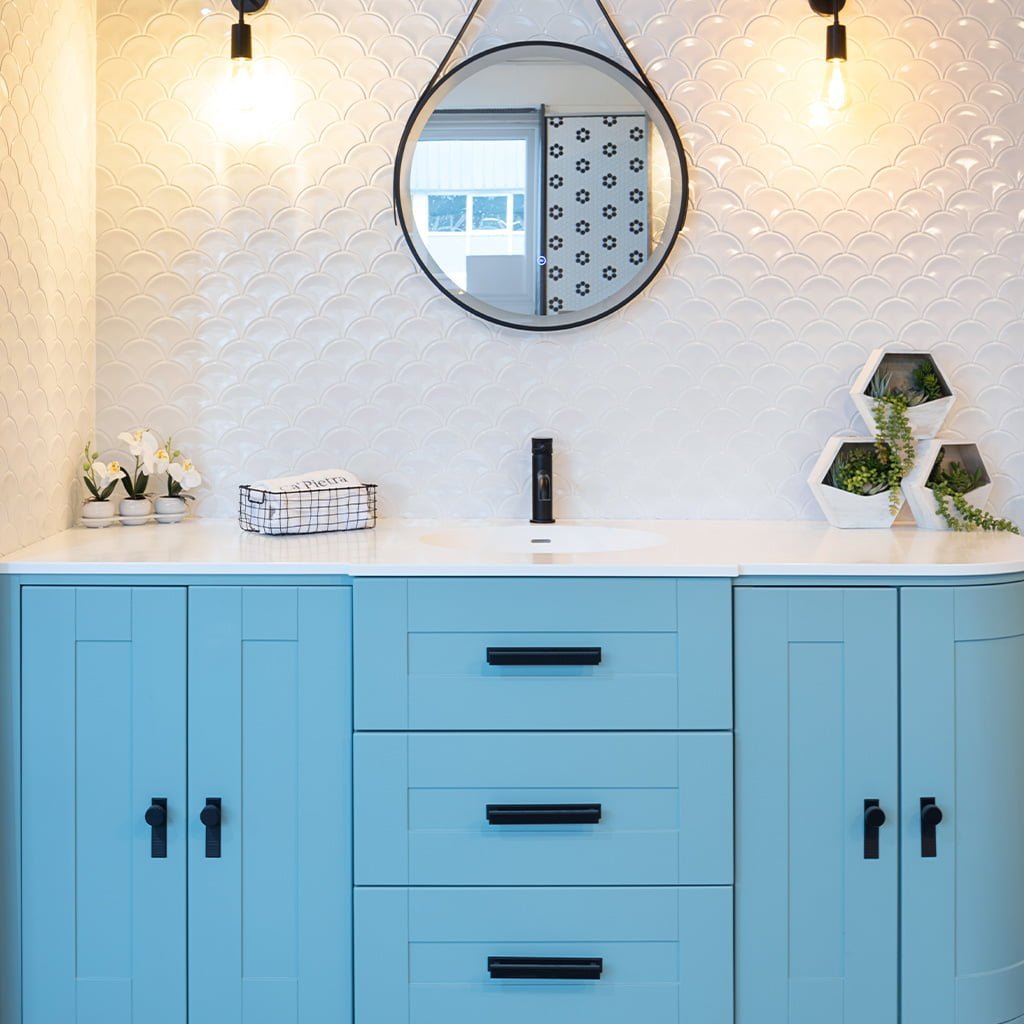 Stylish bathroom with blue cabinets and scalloped tile wall.