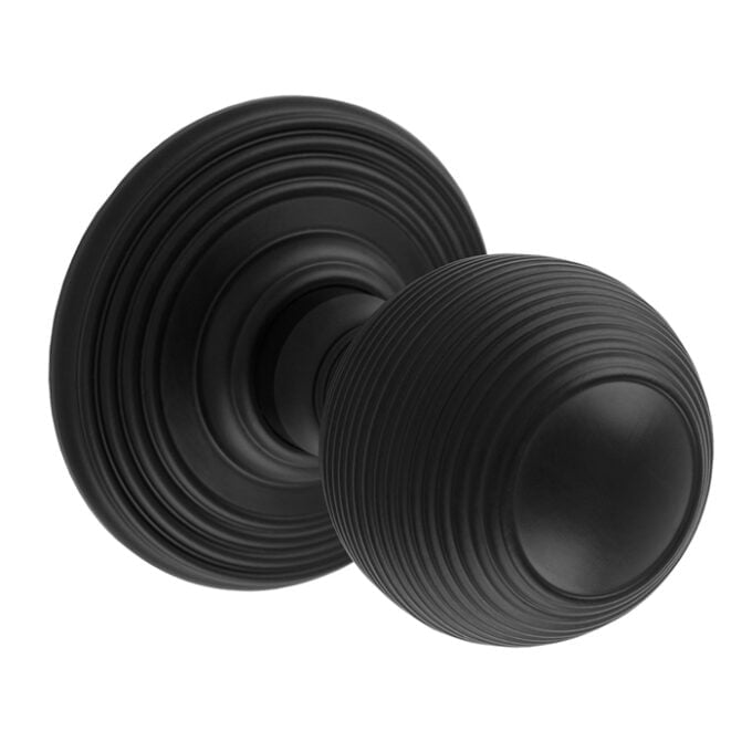 Black ridged door knob on white background.